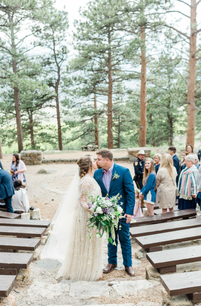 Couple kissing during Wedding Ceremony in Moraine Amphitheatre in Rocky Mountain National Park.
