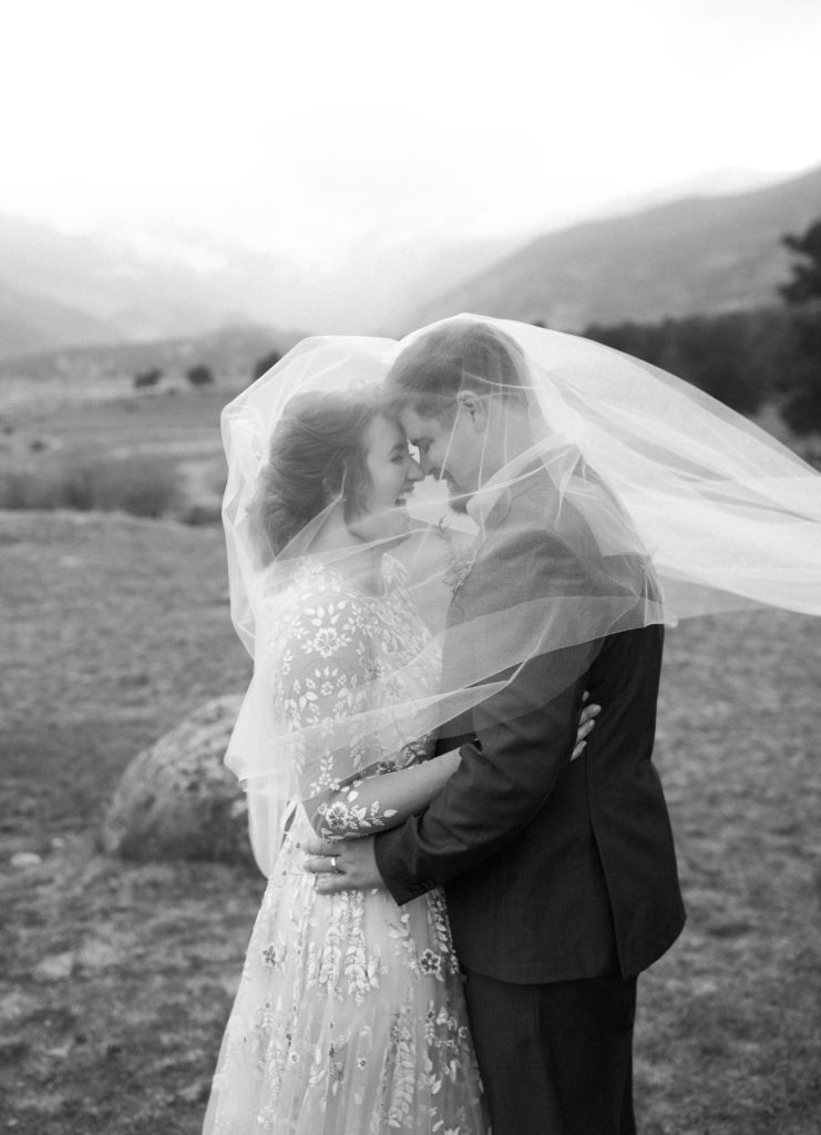 Bride and groom laughing under veil in Rocky Mountain National Park