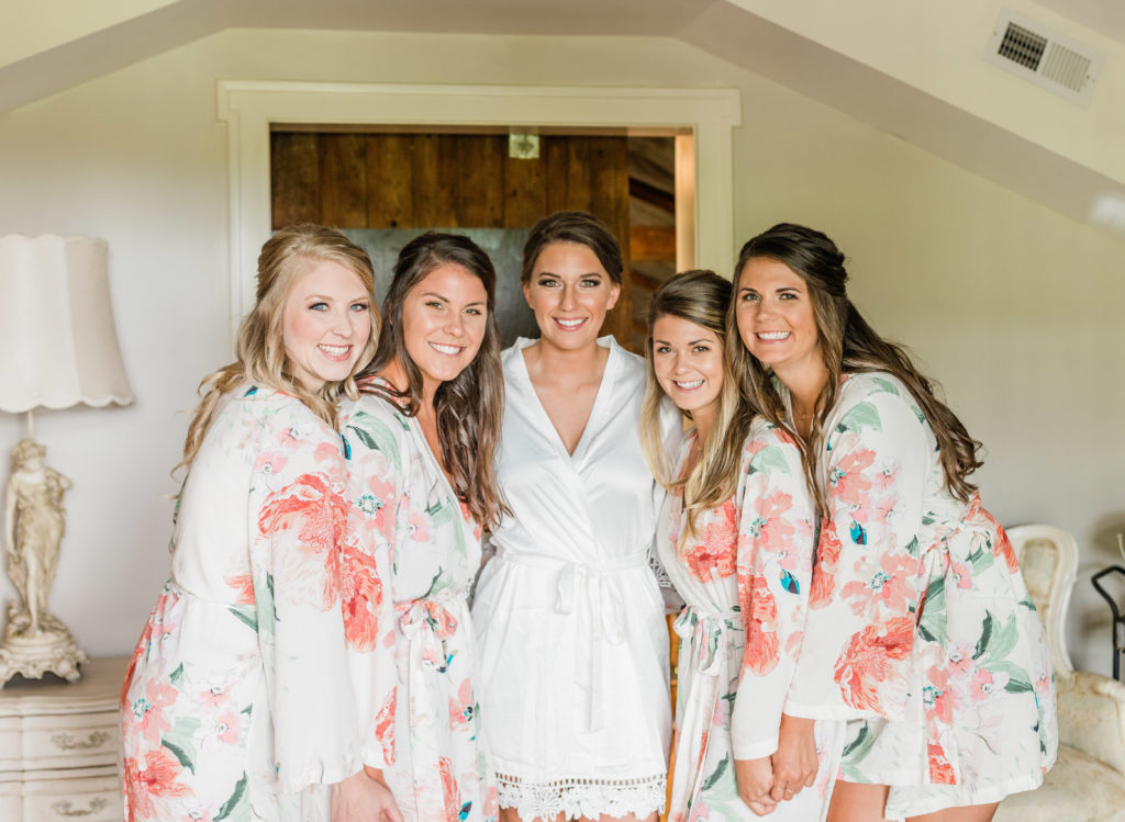 bride with her bridesmaids smiling in robes