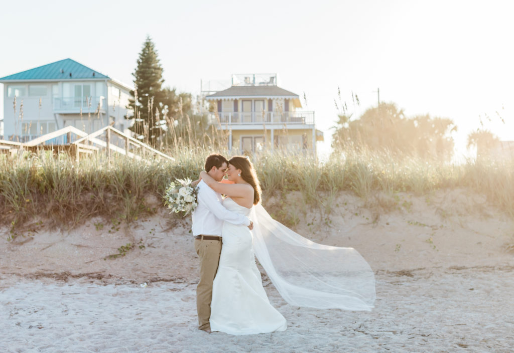 Bride and groom on beach during sunset elopement.
